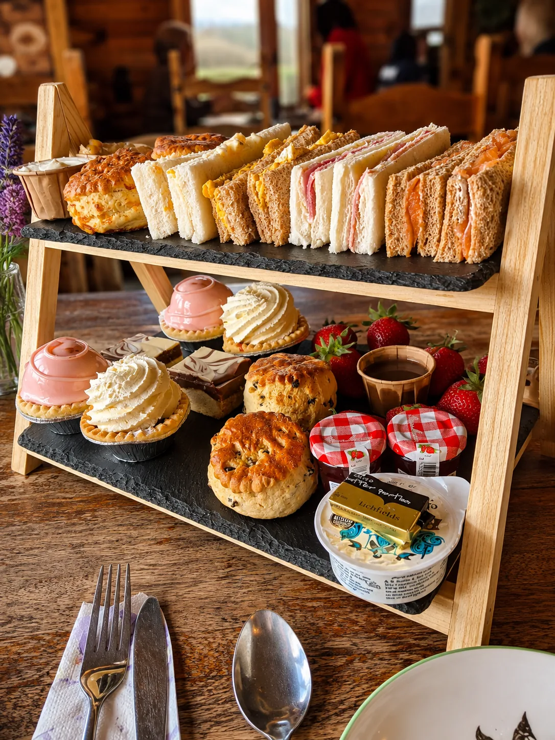 A tiered stand of sandwiches, scones, pastries and preserves